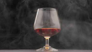 Sert bir alkolik içkisi. Viski, brendi, bardakta konyak ve puro dumanı.
