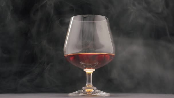 Silný alkoholický nápoj whisky, brandy, koňak ve sklenici s kouřem z doutníku — Stock video