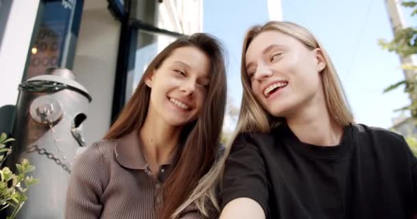 Twee jonge lachende vrouw praten buiten op cafe in de zomer dag, het nemen van selfie — Stockvideo