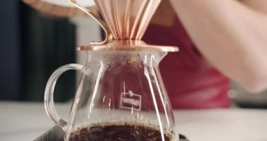 V60 'ın işleyişi, Barista iş yerinde bir fincan koyu kahveyi kağıt filtreye çevirir. 