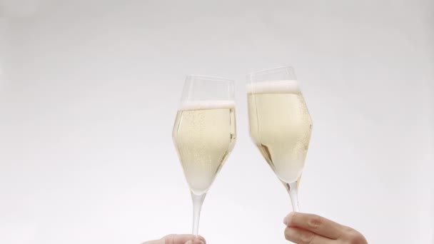 İki kadeh şampanya yaklaşıyor ve yavaş çekimde beyaz arka planda çarpışıyor. — Stok video