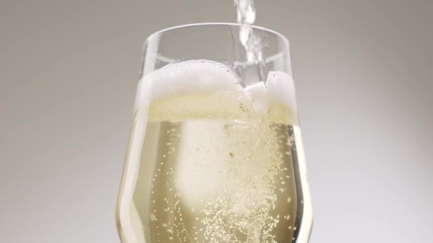 Butelkę szampana wlewa się do szklanki musującej na białym tle. — Wideo stockowe