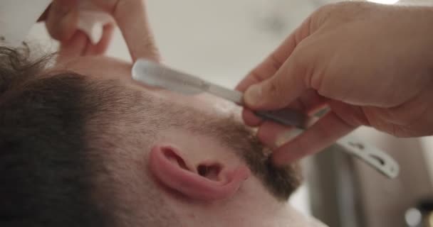 Peluquero profesional afeita la barba del cliente con afeitadora recta — Vídeo de stock