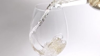 Beyaz arka planda, temiz bir bardaktan bardağa beyaz şarap dökmek