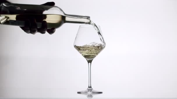 Наливання білого вина з прозорого келиха в склянку на білому тлі — стокове відео