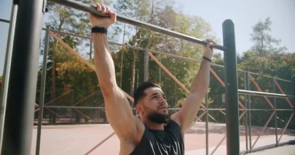 Een gespierde man traint Up In Public Gym. Gezonde man op pull-up bars Oefenen — Stockvideo