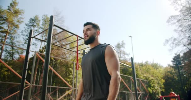 Un bărbat musculos la sala de sport în aer liber, pregătindu-se să facă exerciții fizice, să ia o pauză, să se bucure — Videoclip de stoc