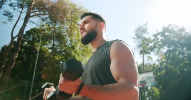 Bărbat sportiv ridicând greutăți cu ambele mâini într-un parc public, antrenament Biceps — Videoclip de stoc