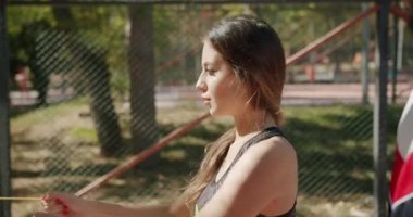 Kişisel antrenörü olan sporcu bir kadın dışarıda direniş bandıyla egzersiz yapıyor.