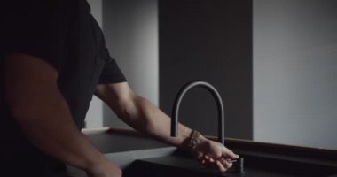 Modern bir mutfakta minimalist iç mimarisi olan bir adam greyfurt yıkıyor.