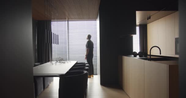 Een man kijkt uit het raam naar een appartement met een modern keukeninterieur — Stockvideo