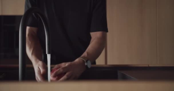 Een man wast een grapefruit in een moderne keuken met een minimalistisch interieur — Stockvideo