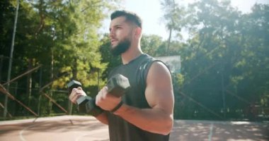 Halka açık bir parkta iki eliyle ağırlık kaldıran sporcu.