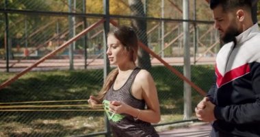 Kişisel antrenörü olan sportif bir kadın mekik çekiyor ve kaslarını kasıyor.