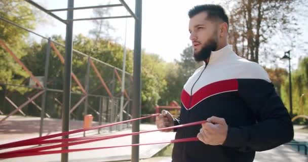 Sportovec dělá odbojové skupiny cvičení, trénink venku s elastickou páskou — Stock video