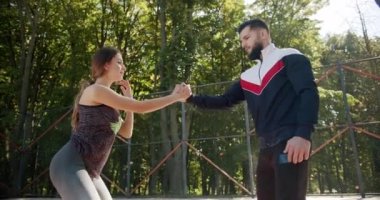 Kişisel antrenörü olan sportif bir kadın mekik çekiyor ve kaslarını kasıyor.