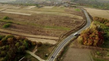 Güzel renkli bir ormanda ilerleyen bir kamyoneti olan düz asfalt bir yol. 