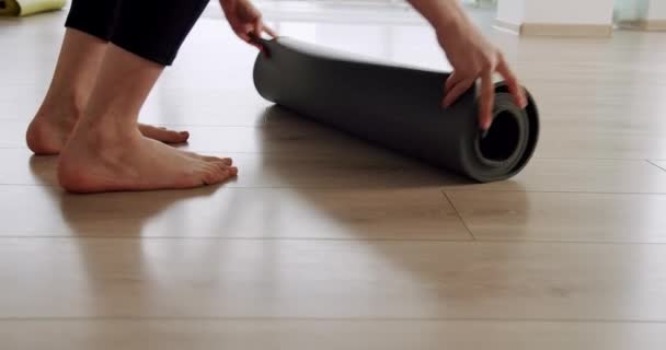 Close-up aantrekkelijke vrouw ontvouwt een tapijt voor het beoefenen van yoga in de studio — Stockvideo