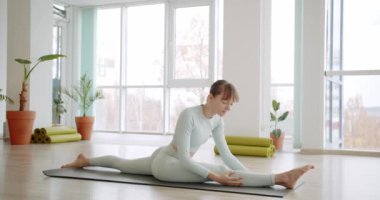 Güzel bir kadın yoga pozisyonunu parlak bir stüdyoda, sabah konseptinde uyguluyor.