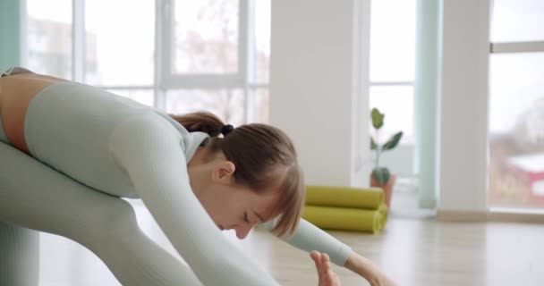 Een mooie vrouw oefent een positie van yoga krijger in de studio, Virabhadrasana — Stockvideo