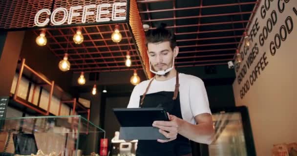Vrolijke jonge mannelijke cafe eigenaar op zoek naar koffie recepten met behulp van digitale tablet — Stockvideo