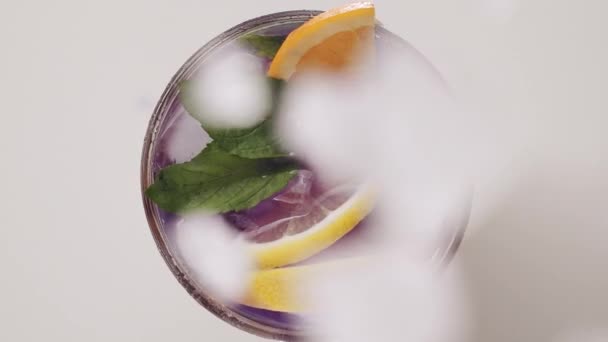 Jégdarabok esnek bele egy pohár frissítő nyári limonádé koktélba mentával — Stock videók