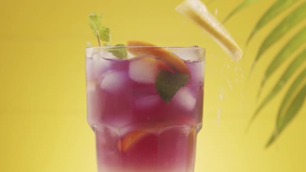 Pezzi di ghiaccio e lime cadono in un bicchiere di rinfrescante cocktail estivo alla limonata — Video Stock