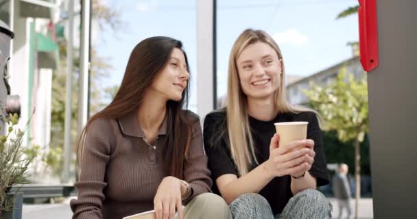 Zwei Mädchen trinken Kaffee und unterhalten sich an einem Sommertag im Open-Air-Café — Stockvideo