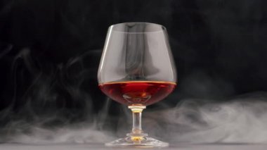 Arka planda duman olan bir bardak viskinin içine bir damla düşer.