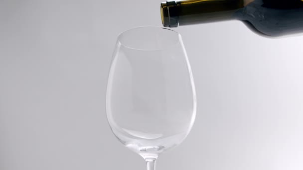 Versare il vino rosso in un bicchiere trasparente su fondo bianco, al rallentatore — Video Stock