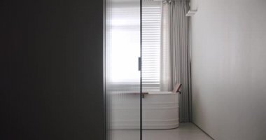 Modern banyoda saydam sürgülü kapı açılıyor, minimalist küvet.