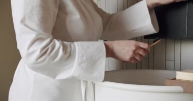 Kadınların elleri modern bir musluğu lavabo, minimalist iç mekan ve aksesuarlarla açar.