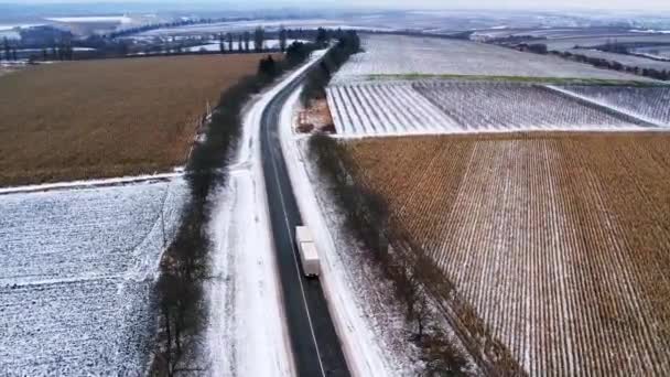 The driving of the loaded truck goes on a route with snow and beautiful fields — 图库视频影像