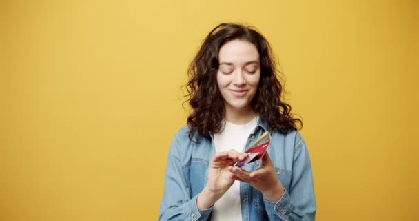 Счастливая улыбающаяся девушка позирует с кредиткой в руке, снятая в студии. — стоковое видео