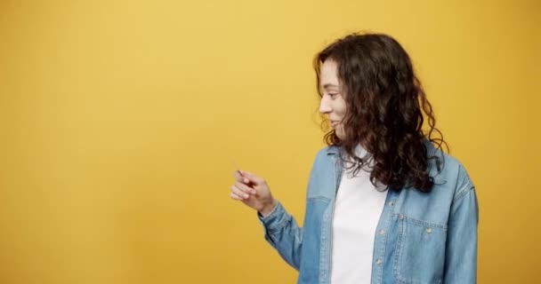 Bir kız kredi kartı alır ve mutlu bir şekilde sarı arka plan stüdyosuna çekilir.. — Stok video