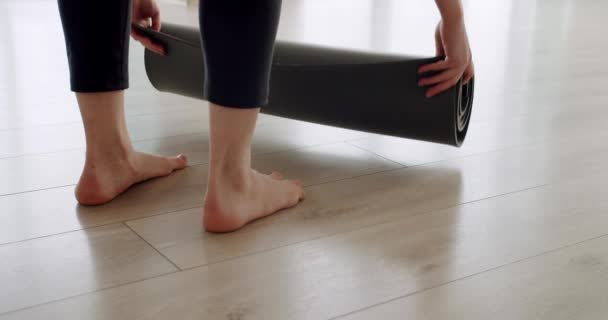 Close-up aantrekkelijke vrouw ontvouwt een tapijt voor het beoefenen van yoga thuis — Stockvideo