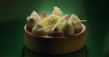 Yeşil arka planda beyaz, kahverengi kremalı tatlı.