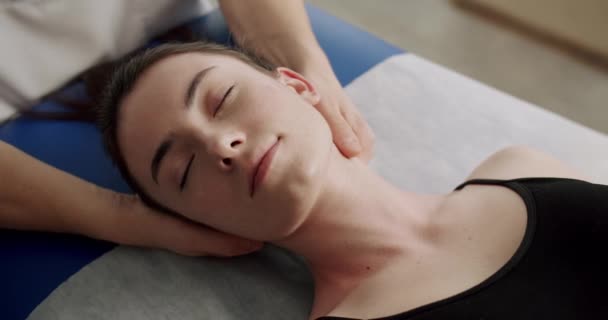 リラックスした女性はマッサージセラピストによる頭マッサージスパ治療のためにベッドに横たわっています — ストック動画