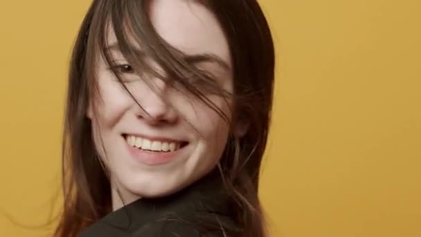 A jovem com cabelo voador olha com um sorriso, feliz. toca no cabelo dela — Vídeo de Stock