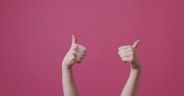 Mujer señala el pulgar hacia arriba contra un fondo rosa aislado. gestos de la mano aprobación — Vídeo de stock