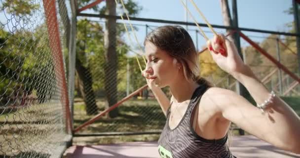 Una joven atleta hace ejercicios con una banda elástica. — Vídeos de Stock