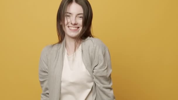 Vrouw glimlachen dansen op muziek ritmisch naar verslaan bewegen op gele achtergrond — Stockvideo