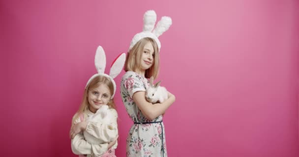 Meninas bonitos com orelhas de coelho brincando com o coelho em um fundo isolado — Vídeo de Stock