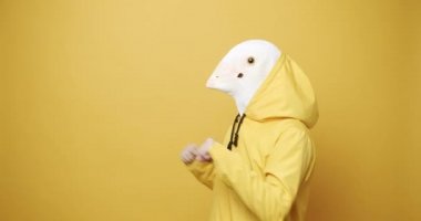 Mutlu Adam, Güvercin Maskesiyle Dans Ediyor sarı arka planda. Aptallar Günü.