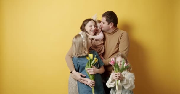 Мати батько і діти обіймаються, розважаючись і позує на жовтому тлі — стокове відео