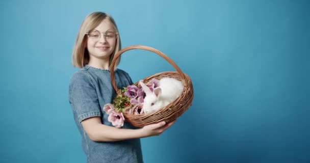 A adolescente de vestido azul segura uma cesta com um coelho na mão — Vídeo de Stock