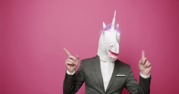 Chico feliz con trajes grises baila con máscara de unicornio. Día de los tontos y abril 1 día. — Vídeo de stock