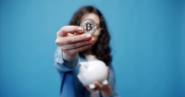 Μια ευτυχισμένη νεαρή γυναίκα κρατά ένα bitcoin με ένα θησαυρό από χρήματα BTC. Κέρμα bit — Αρχείο Βίντεο