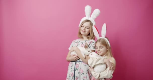 ウサギの耳を持つかわいい女の子は隔離された背景でウサギと遊ぶ — ストック動画