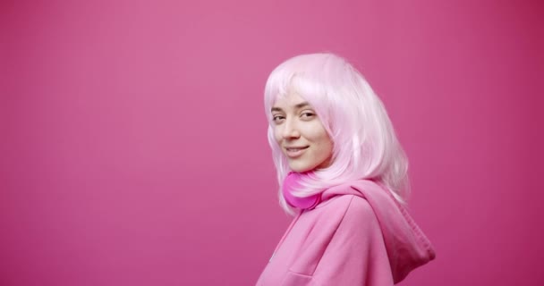 Mujer bastante joven en lleva camiseta y pelo rosa mirando a la cámara. — Vídeo de stock